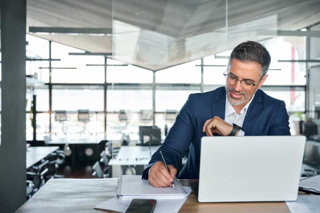 Experienced insurance broker reviewing policies at a modern office desk in the UK.