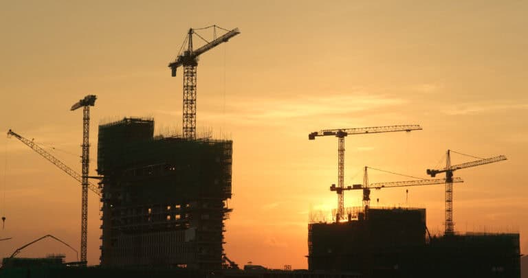 Construction site with cranes at sunset, industrial building under development in the UK.