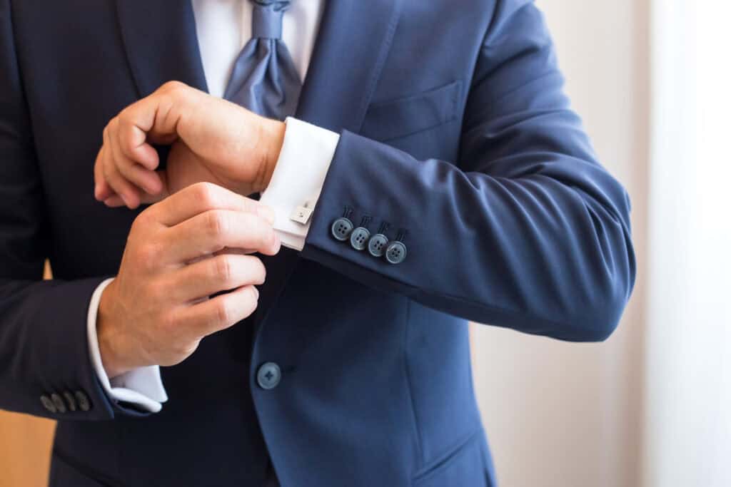 Professional insurance broker adjusting cufflinks in formal suit.