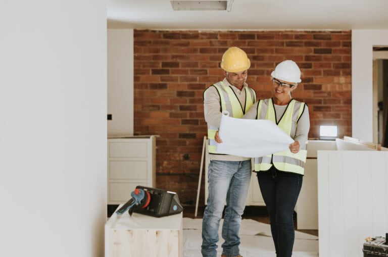 Blueprint review by construction professionals at indoor site, representing commercial insurance services.