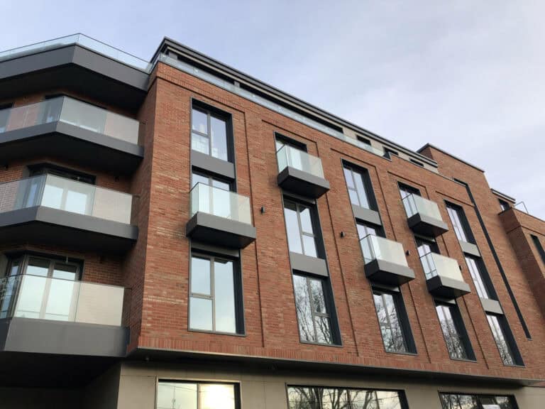 Modern apartment building with glass balconies and brick facade, residential property insurance expert.