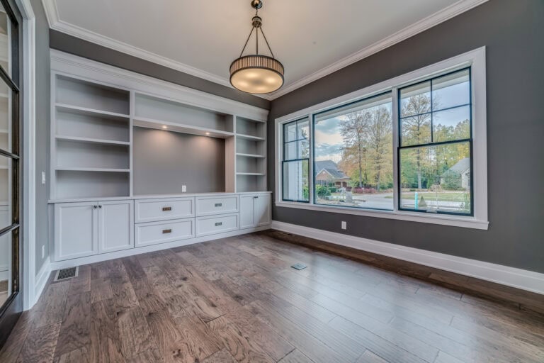 Elegant living room with large window and custom built-in shelving, showcasing home interior design expertise.