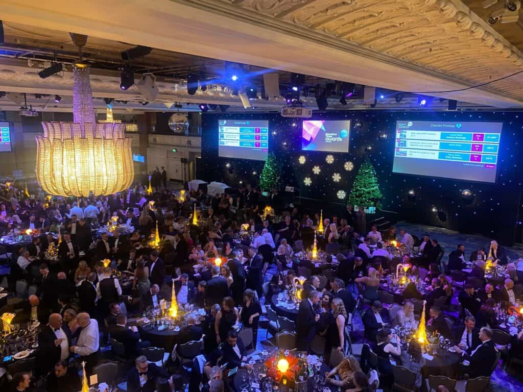 Professional awards ceremony with guests seated at decorated tables in an elegant venue.