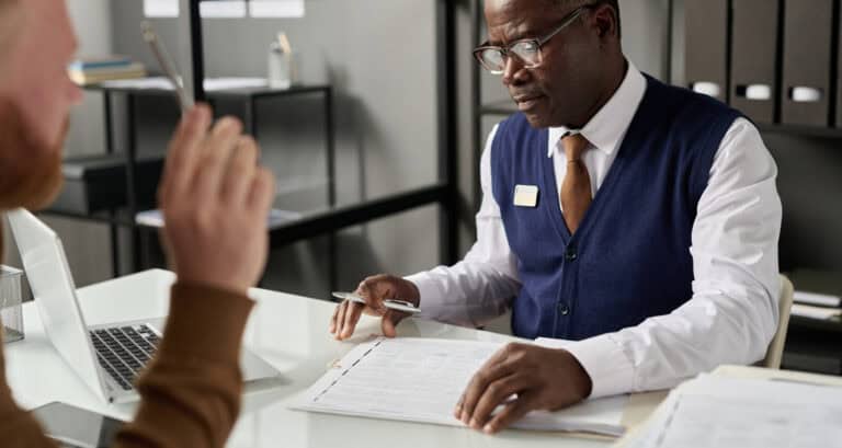 Professional insurance broker discussing policies and coverage options at a modern office desk.
