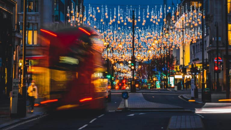 Car driving through a festive illuminated city street at night in London, UK.