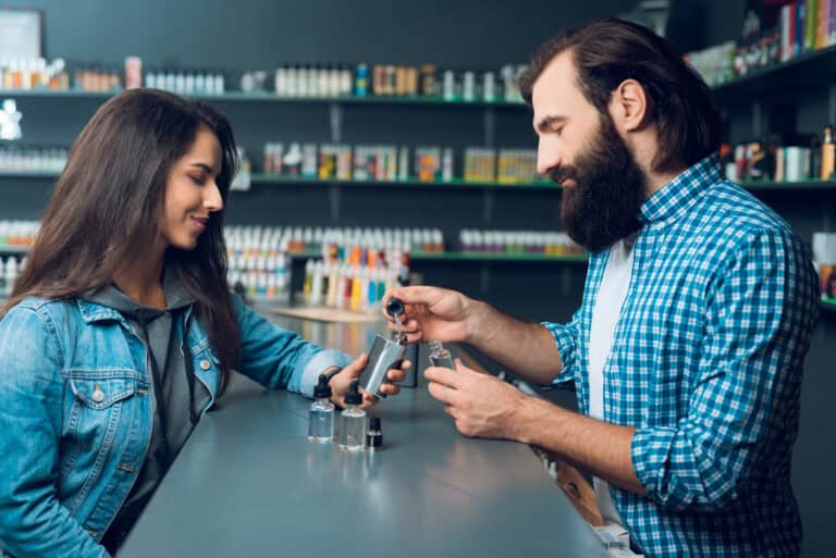 Vape shop owner helping customer with e-liquid selection, professional vape advice, and e-cigarette accessories.