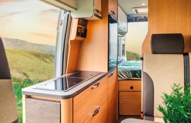 Motorhome interior with kitchen and sleeping area, comfortable travel accommodation, ideal for outdoor adventure holidays.