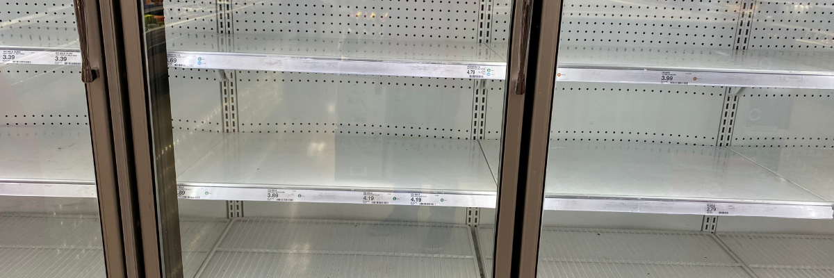 Empty refrigerated supermarket display cabinets with bare shelves after loss of chilled and frozen stock following a refrigeration system failure.